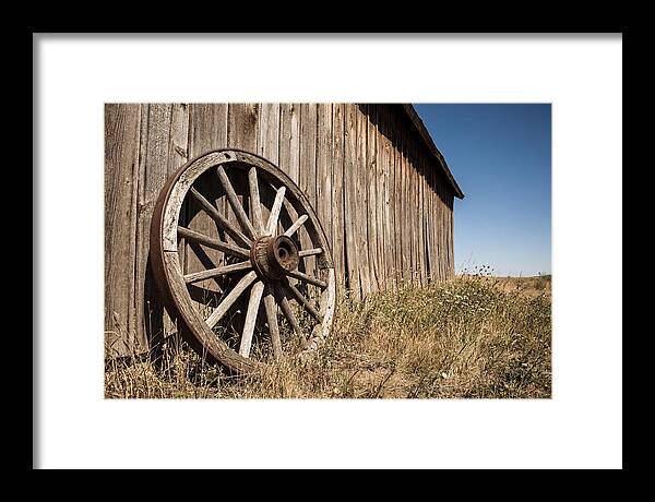 Weathered Wagon Wheel Against Barn