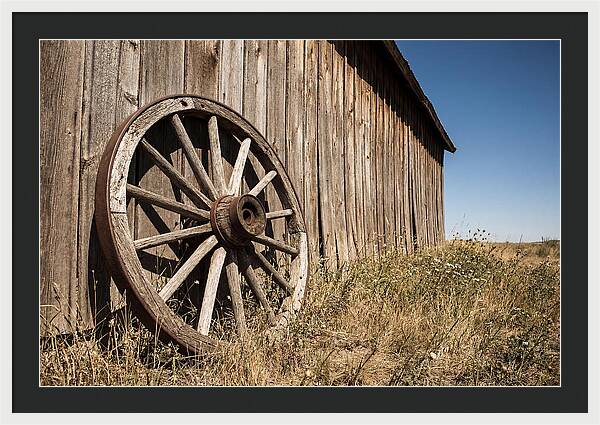 Weathered Wagon Wheel Against Barn