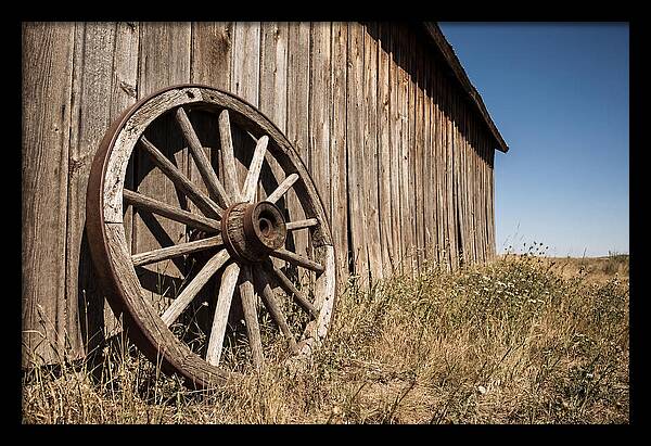 Weathered Wagon Wheel Against Barn