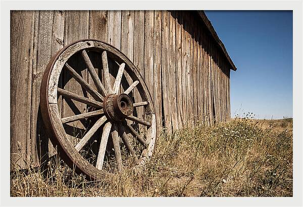 Weathered Wagon Wheel Against Barn