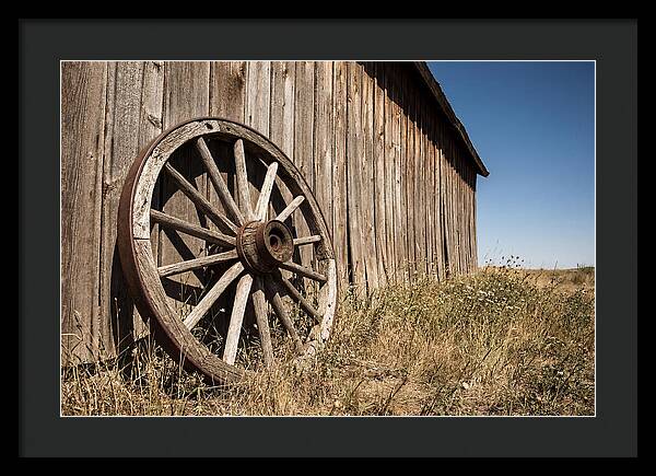 Weathered Wagon Wheel Against Barn