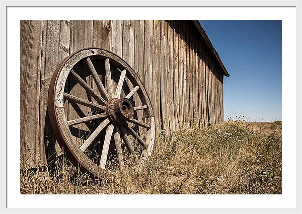 Weathered Wagon Wheel Against Barn