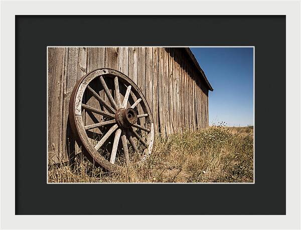 Weathered Wagon Wheel Against Barn