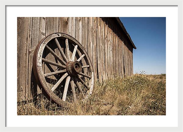 Weathered Wagon Wheel Against Barn
