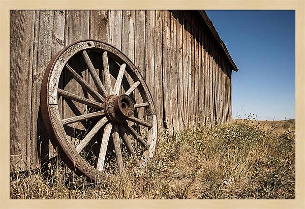 Weathered Wagon Wheel Against Barn