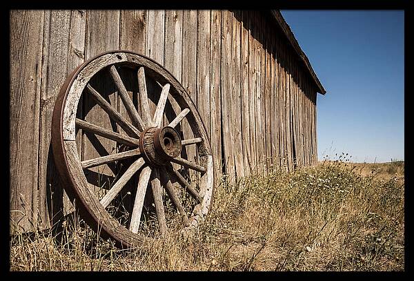 Weathered Wagon Wheel Against Barn