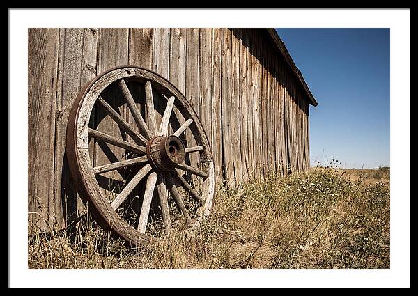 Weathered Wagon Wheel Against Barn