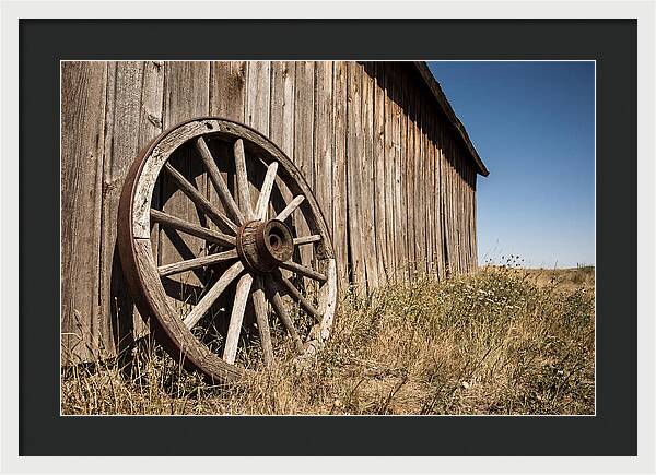 Weathered Wagon Wheel Against Barn
