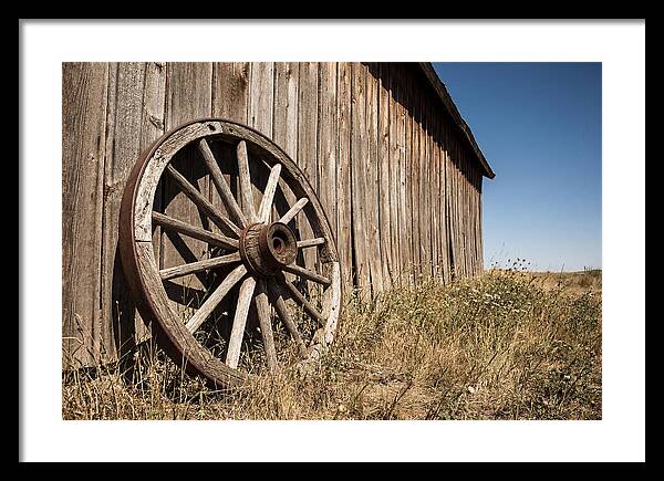 Weathered Wagon Wheel Against Barn