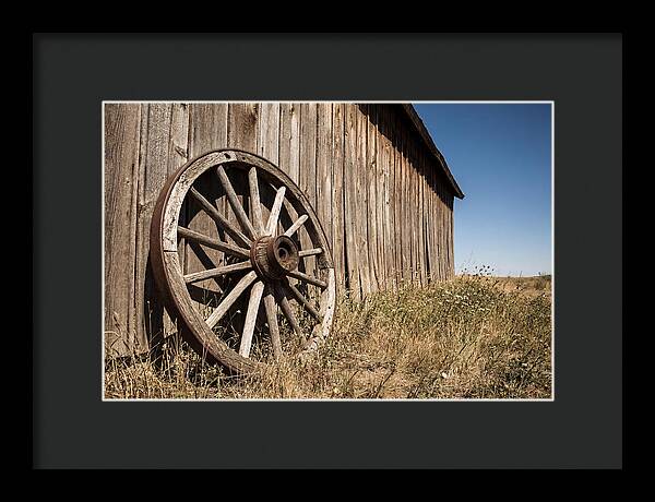 Weathered Wagon Wheel Against Barn