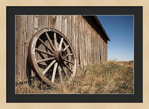 Weathered Wagon Wheel Against Barn