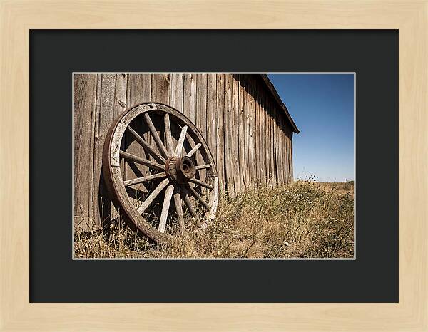Weathered Wagon Wheel Against Barn