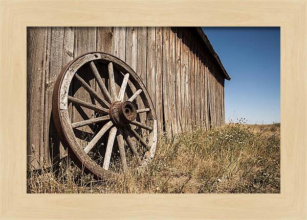Weathered Wagon Wheel Against Barn